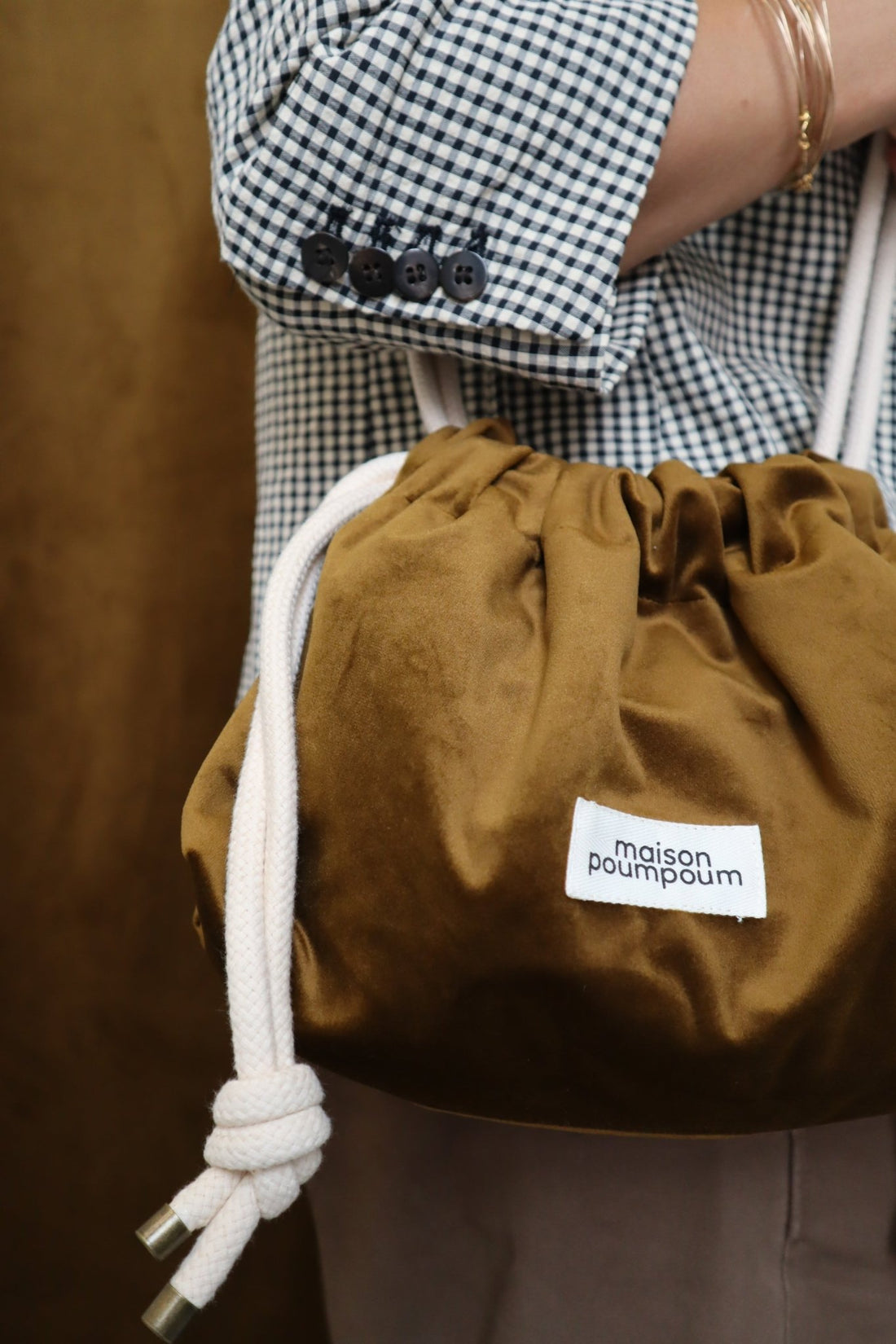 Sac bourse en velours bronze Maison Poumpoum porté avec une veste vichy, pièce choisie avec soin par Lili Margaret